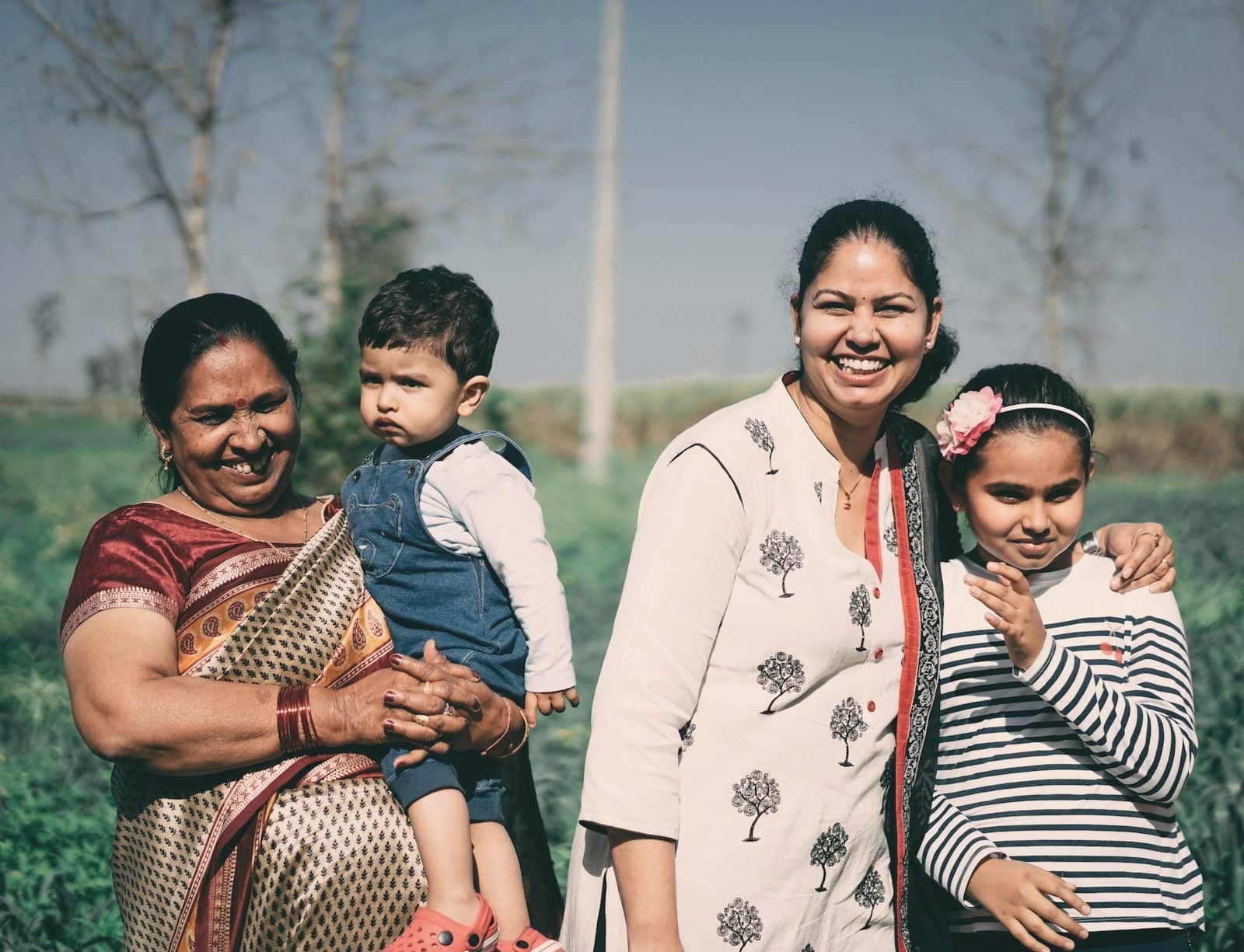 Three generations of an Indian family smiling together outdoors
