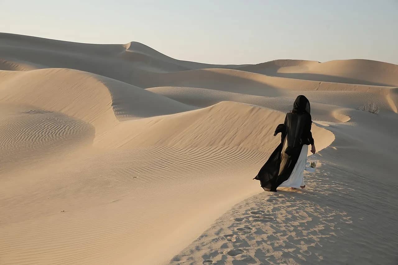 A visitor walking on sand dunes in the UAE desert