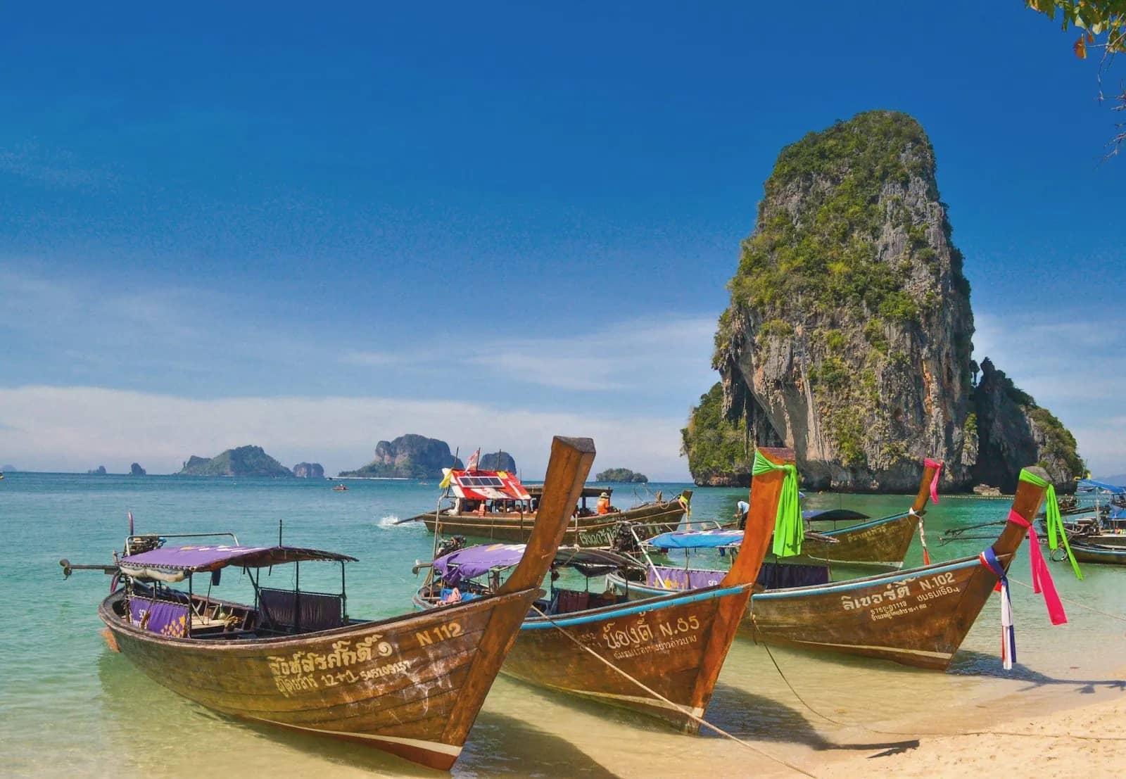 Longtail boats on a Krabi beach in front of a limestone rock